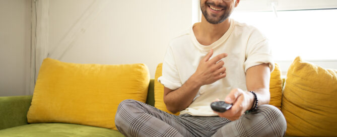 Young man watching TV and having fun at home