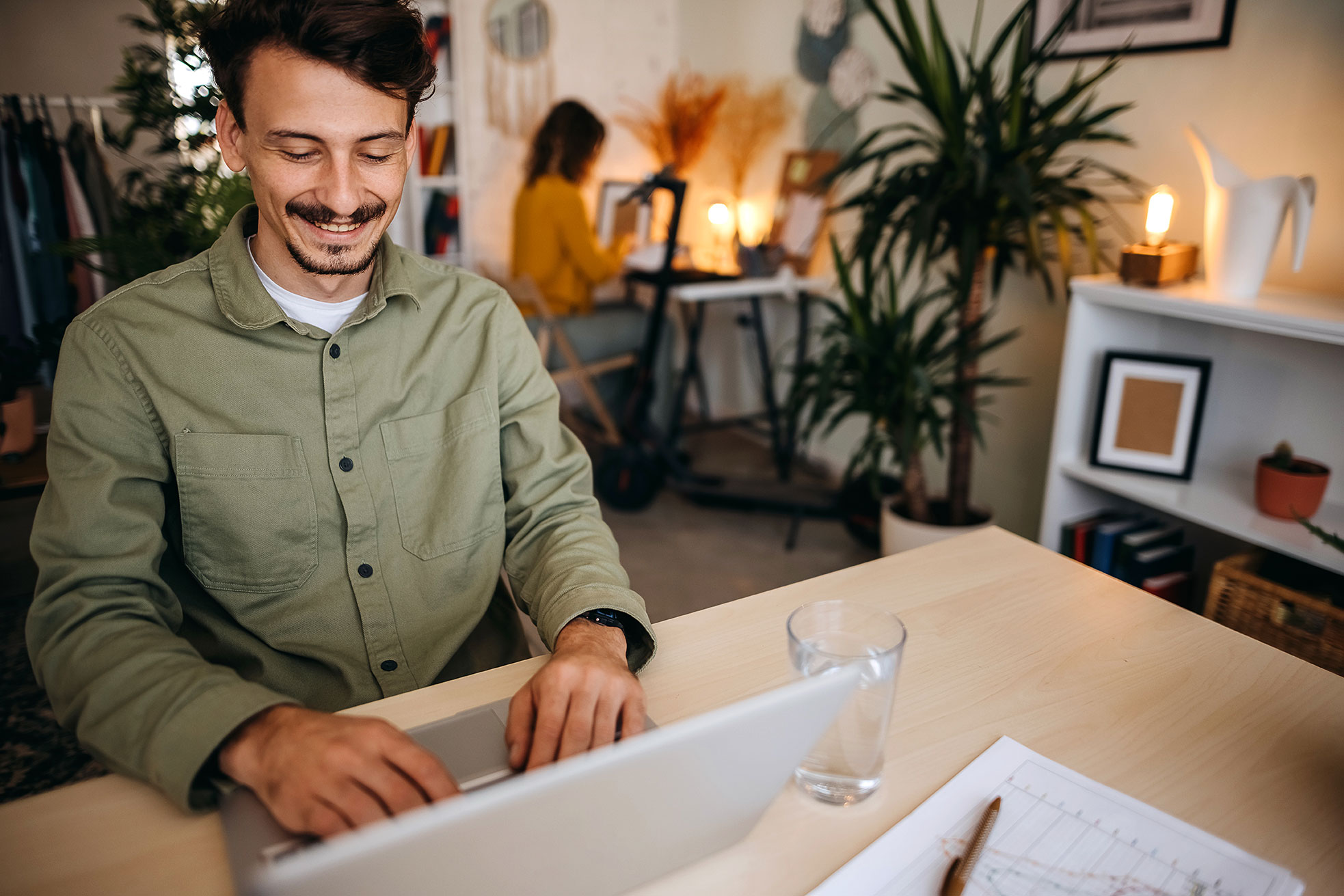 Un jeune homme est assis devant un ordinateur portable dans une agence très agréable et travaille avec satisfaction.