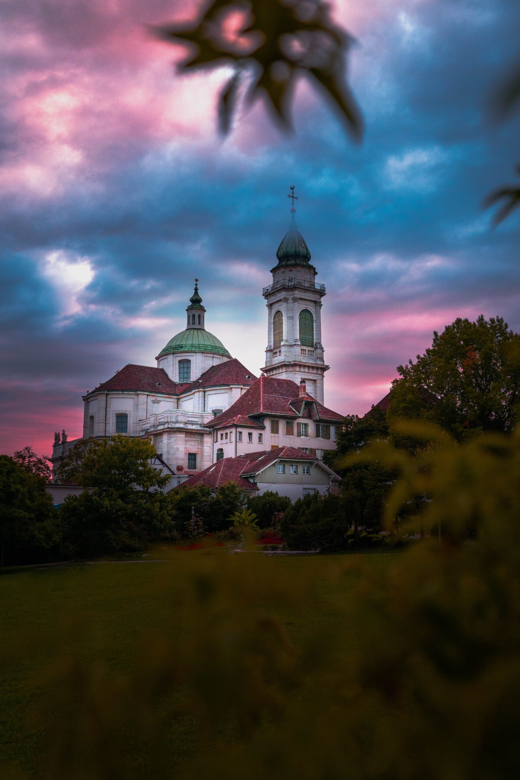 Grande église avec une prairie devant et des nuages sombres qui se forment