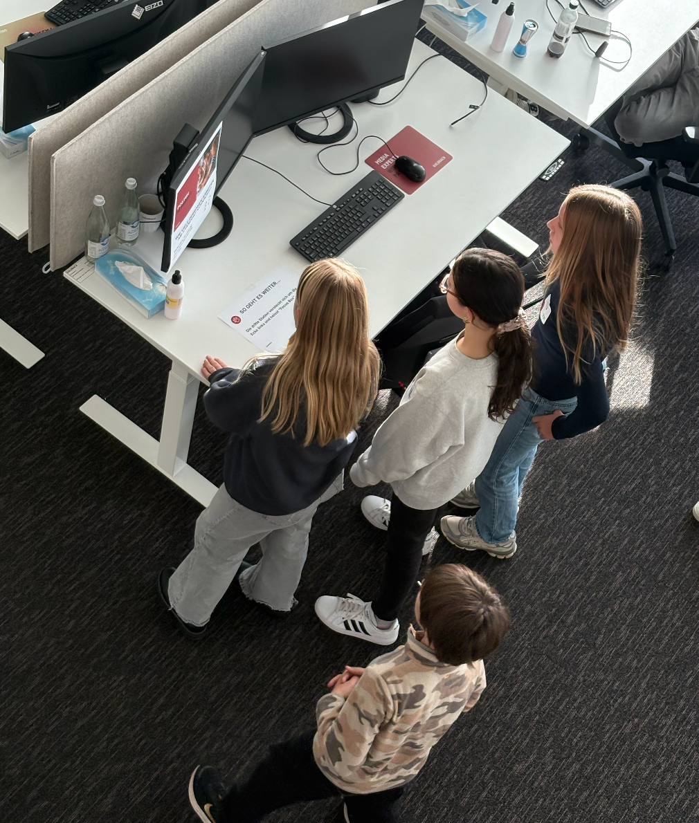 Kinder stehen an einem Arbeitsplatz und versuchen eine Aufgabe zu lösen.