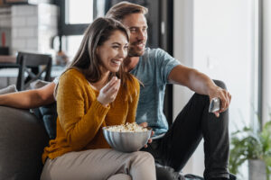 Young couple enjoying their free time together. They watch TV and eat popcorn.