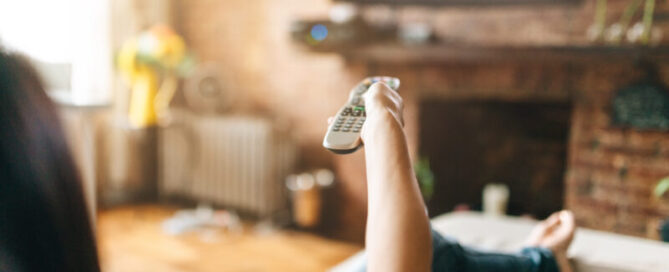Woman sits on the sofa and zaps through the program.