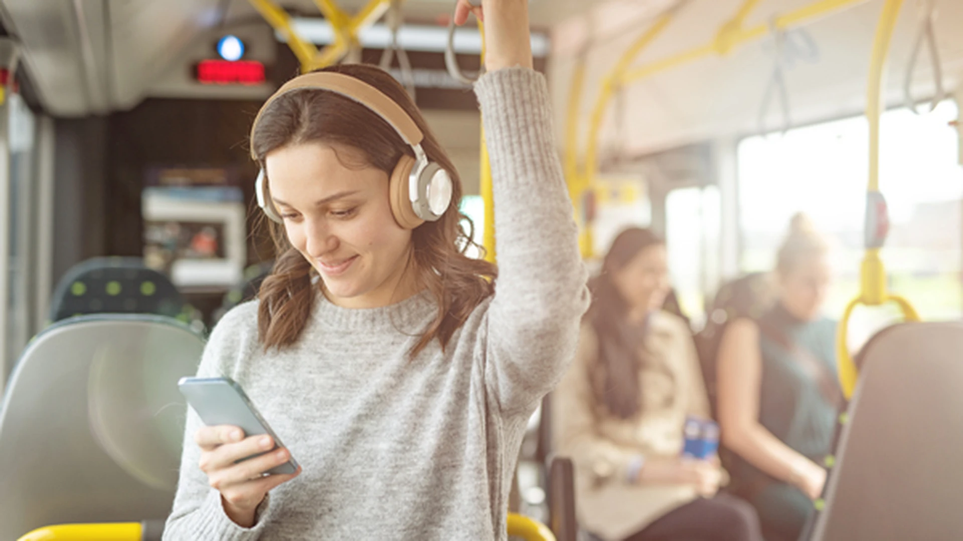 Frau steht im ÖV und hört Audio