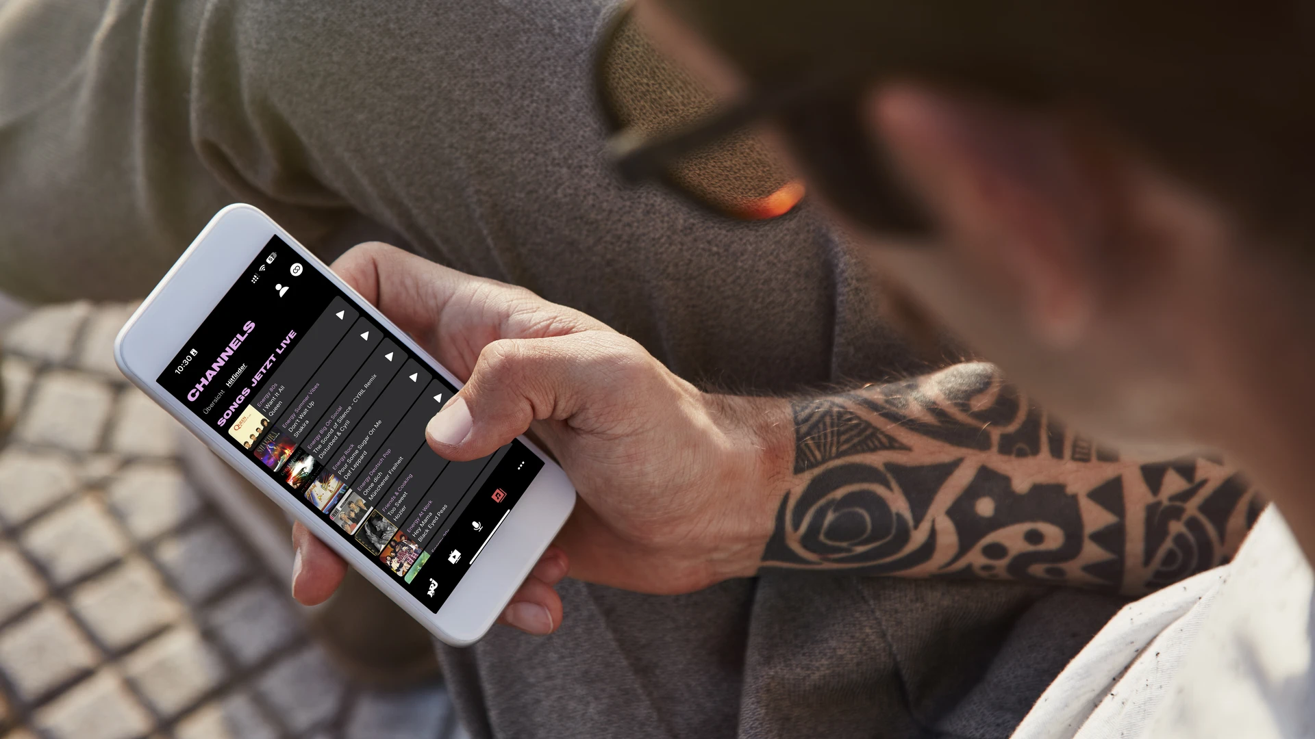 Mann sitzt mit Handy und schaut sich Audio-Platform an