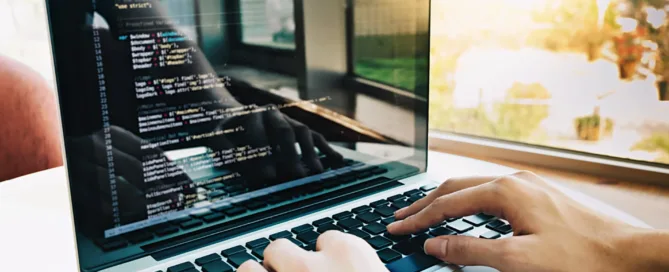 Laptop mit Code und jemand arbeitet daran