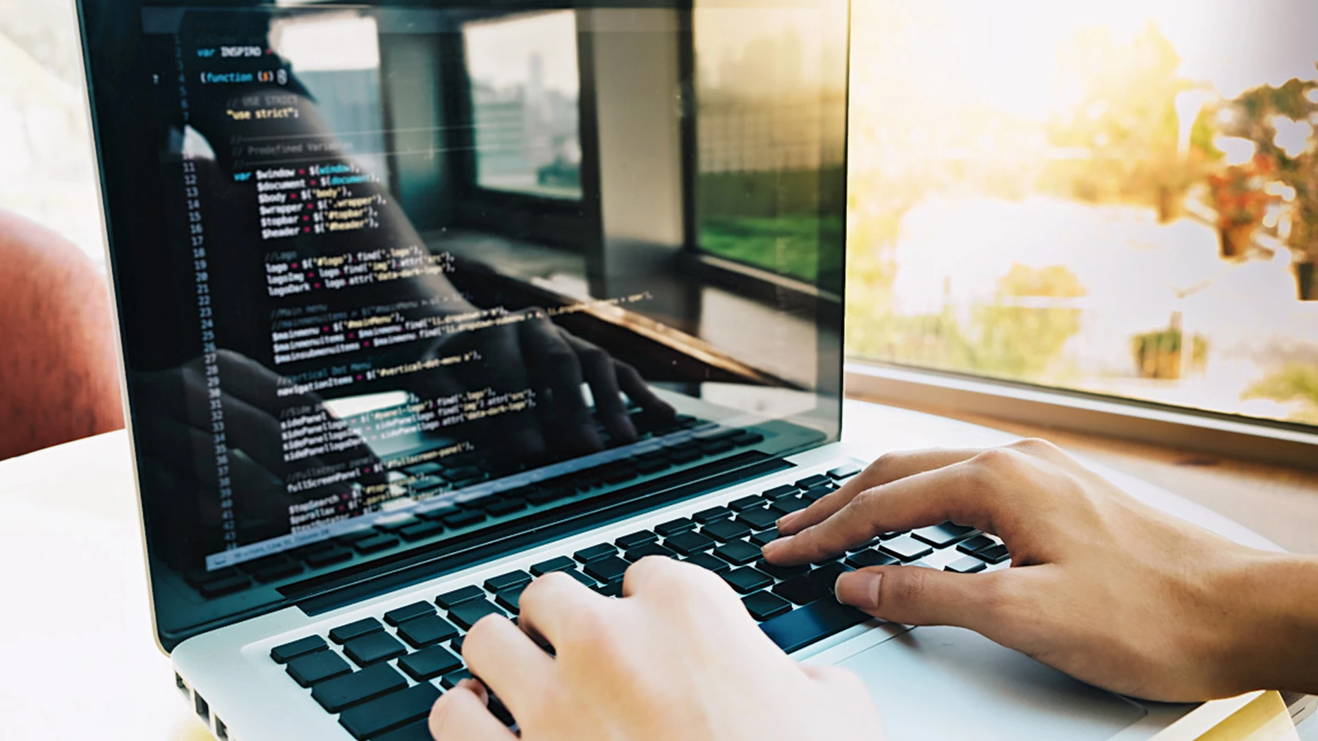 Laptop mit Code und jemand arbeitet daran