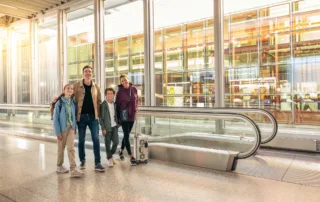 People walking at the airport next to moving walkway