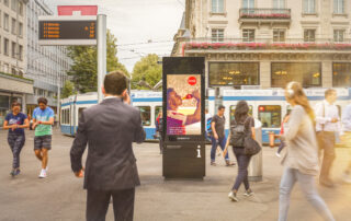 An eCity panel at Paradeplatz with people passing by.