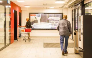 Analog advertising space in a shopping center. One person waiting for the elevator and one person entering the parking garage. 