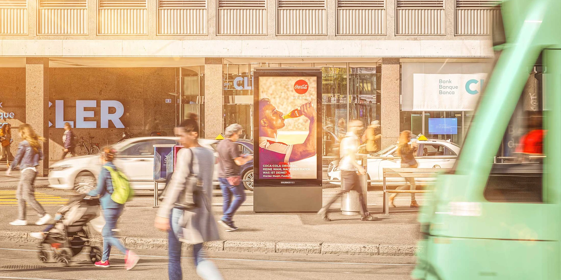 Screen next to a tram stop with people walking past