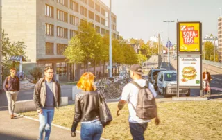 Two billboards with people walking past