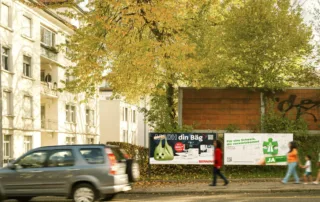 Billboards on the street side in the city of St. Gallen with people passing by.