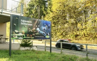 A double-sided advertising space next to a road. A car is driving past 