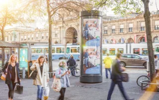The image shows an illuminated rotating column at Bahnhofplatz Zurich.