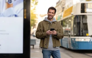 Person next to advertising space and a passing tram