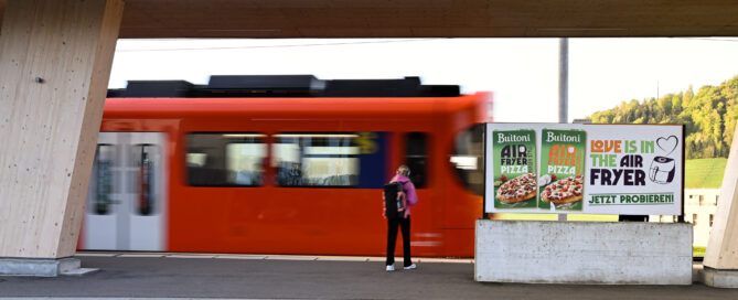 Werbefläche mit Person, welche auf Tram wartet
