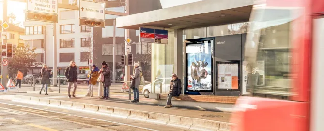 Screen an der Tramstation mit Personen, welche warten