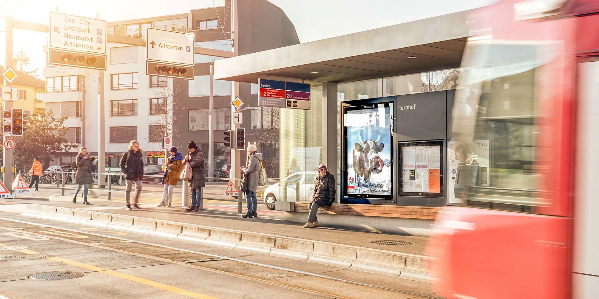 Screen at the tram station with people waiting